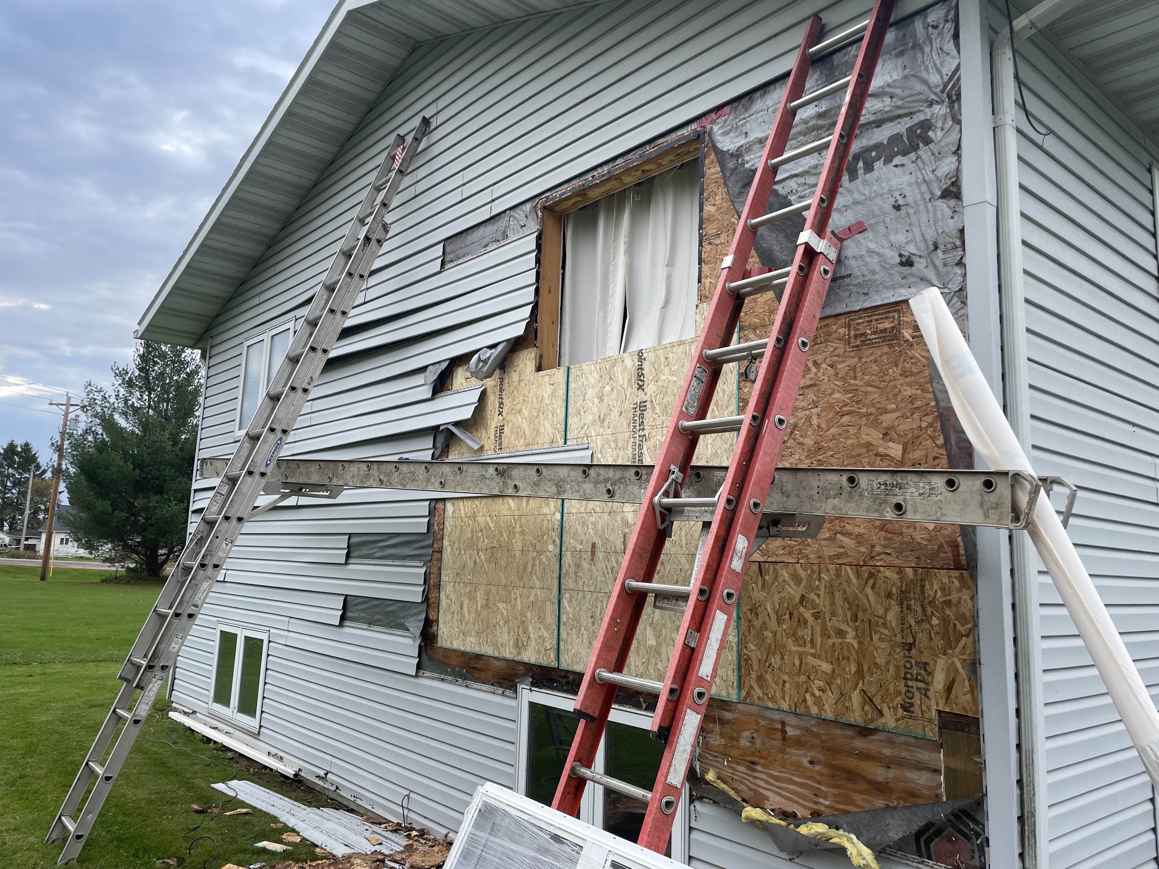 Siding removed exposing sheathing and new window opening during exterior remodel